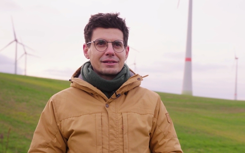 Sebastian Kupfer, Mitgründer der Energiegenossenschaft Helmetal mit Windpark im Hintergrund